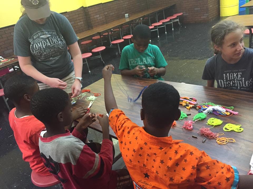 Adult and children at a table with craft supplies