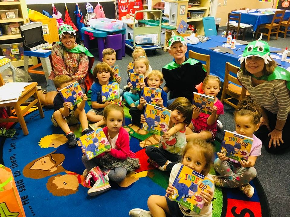 Adults and children in a classroom holding books