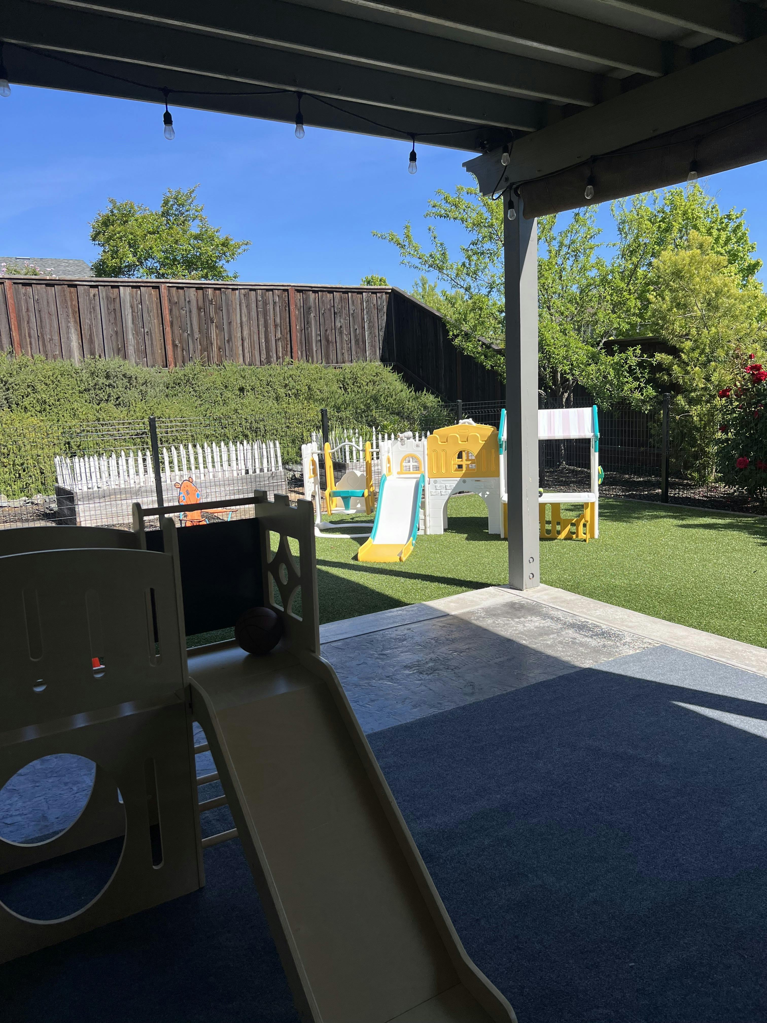 An outdoor play area with a small basketball and slides