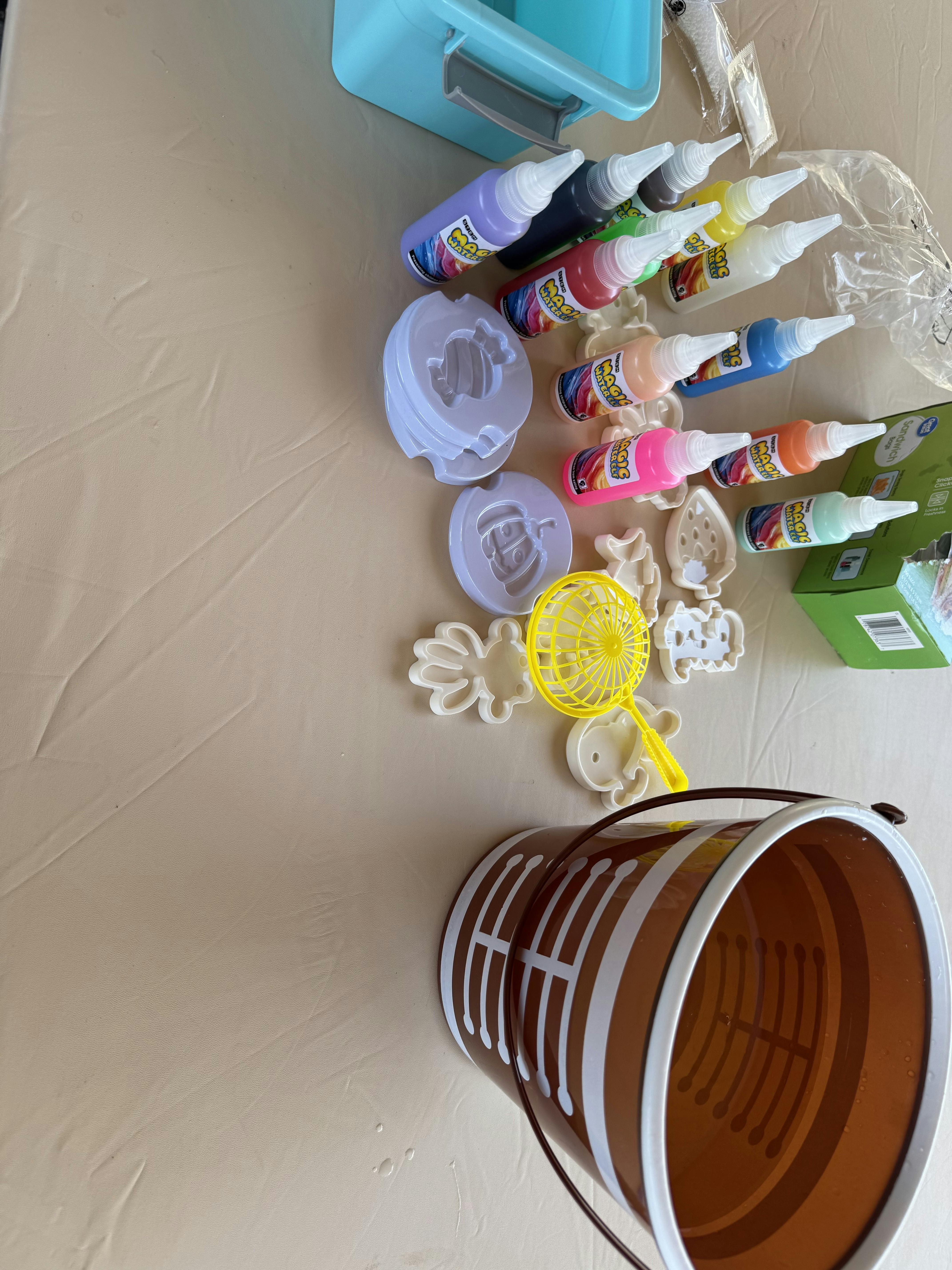 multiple bottles of colorful crafting liquid, molds, and cookie cutters on a table