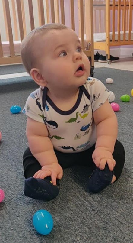 Child sitting on a carpeted floor looking up