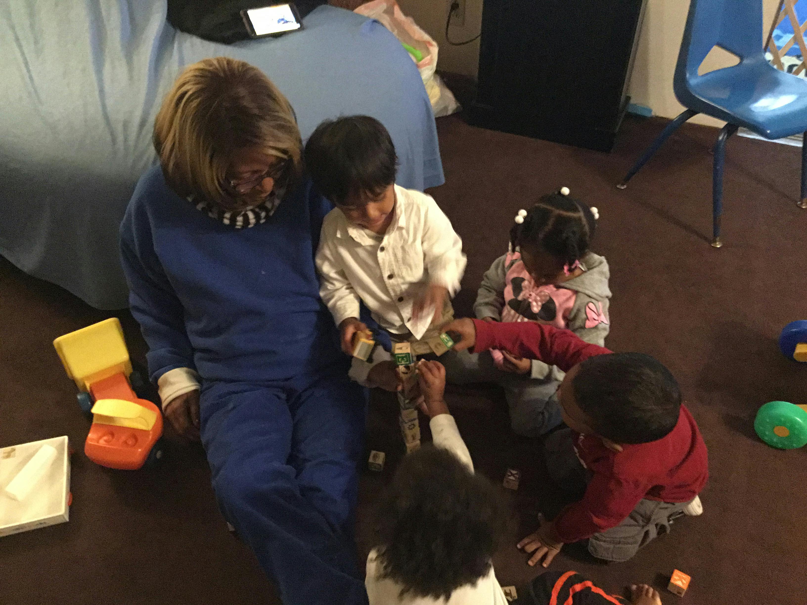 Person and multiple children playing with blocks on the floor