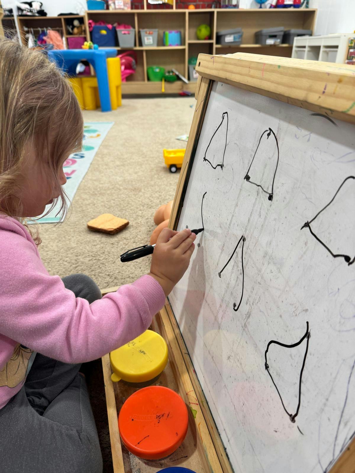 Child drawing on a whiteboard in a classroom