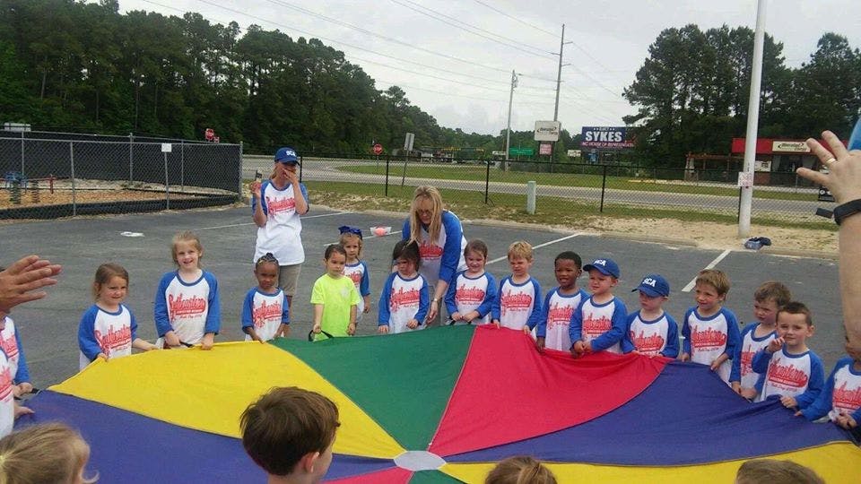 Children and adults holding a colorful parachute outdoors