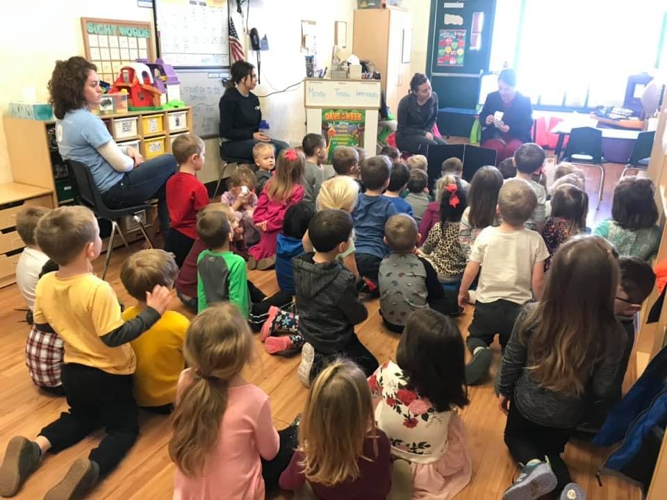 Adults and children sitting on the floor in a classroom