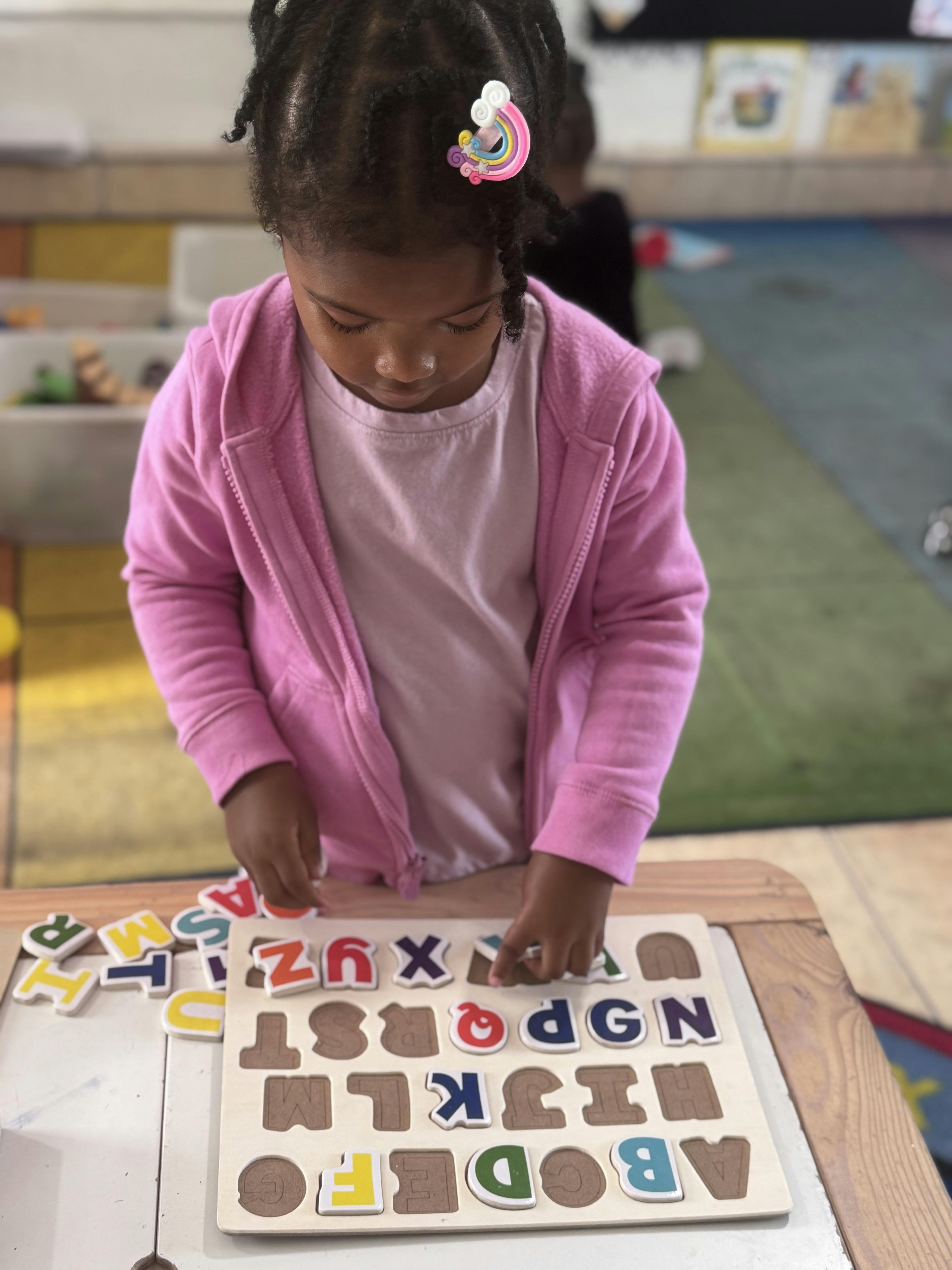 Child playing with an alphabet puzzle in a classroom