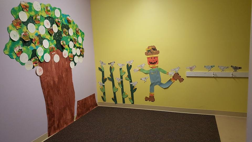 Wall decorations of a tree and a scarecrow with corn stalks