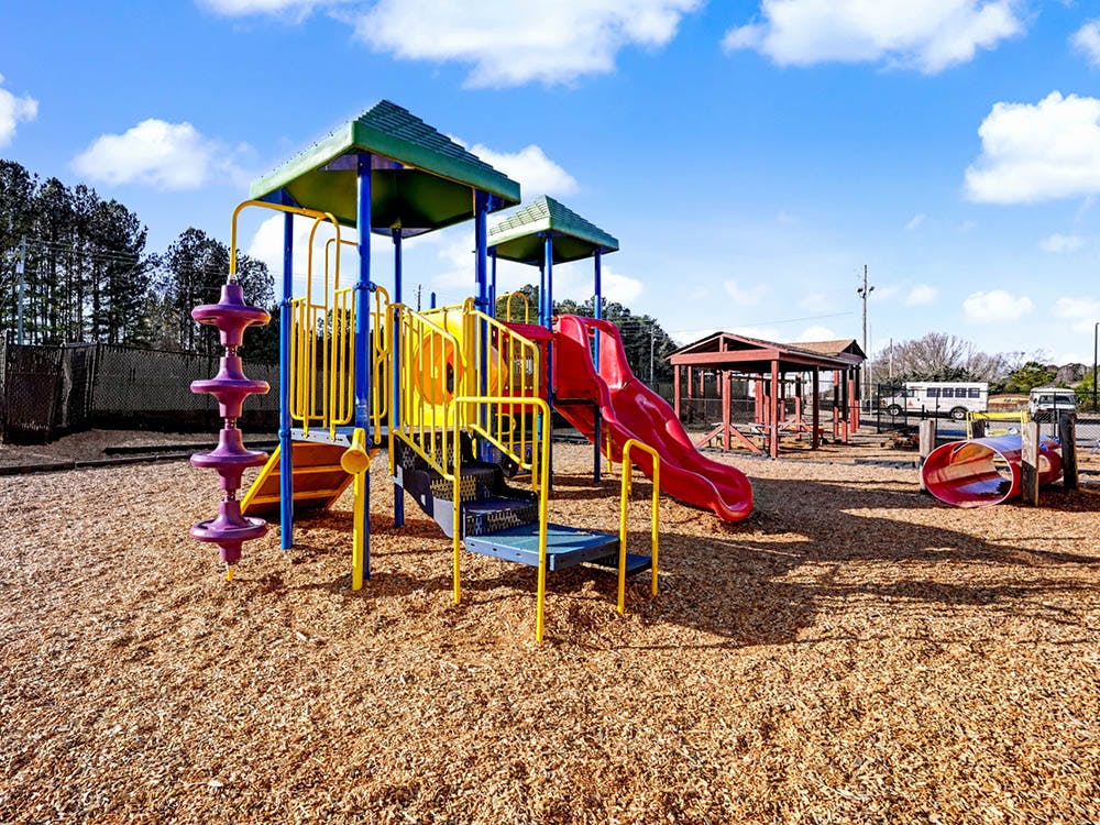 Colorful playground structure with slides and climbing features on wood chips
