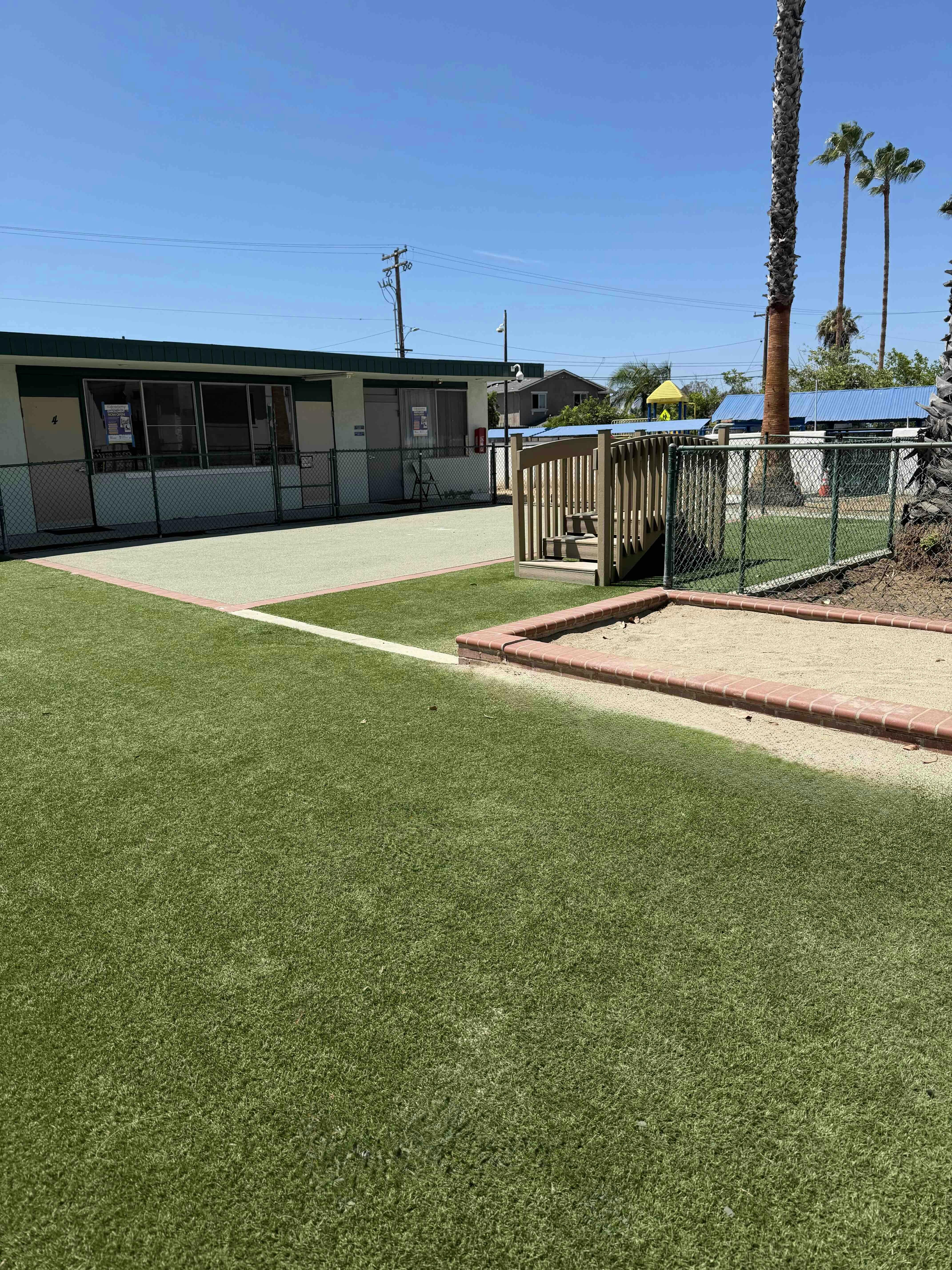 Playground with artificial turf and a sandpit next to a school building