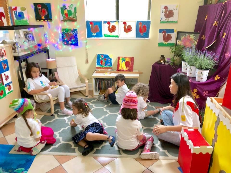 Adult and children sitting on floor and chair in a classroom
