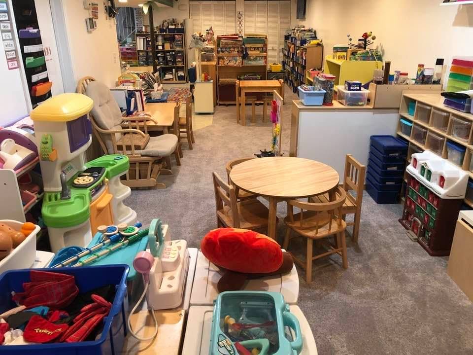 Playroom with small tables and chairs, shelves, and various toys