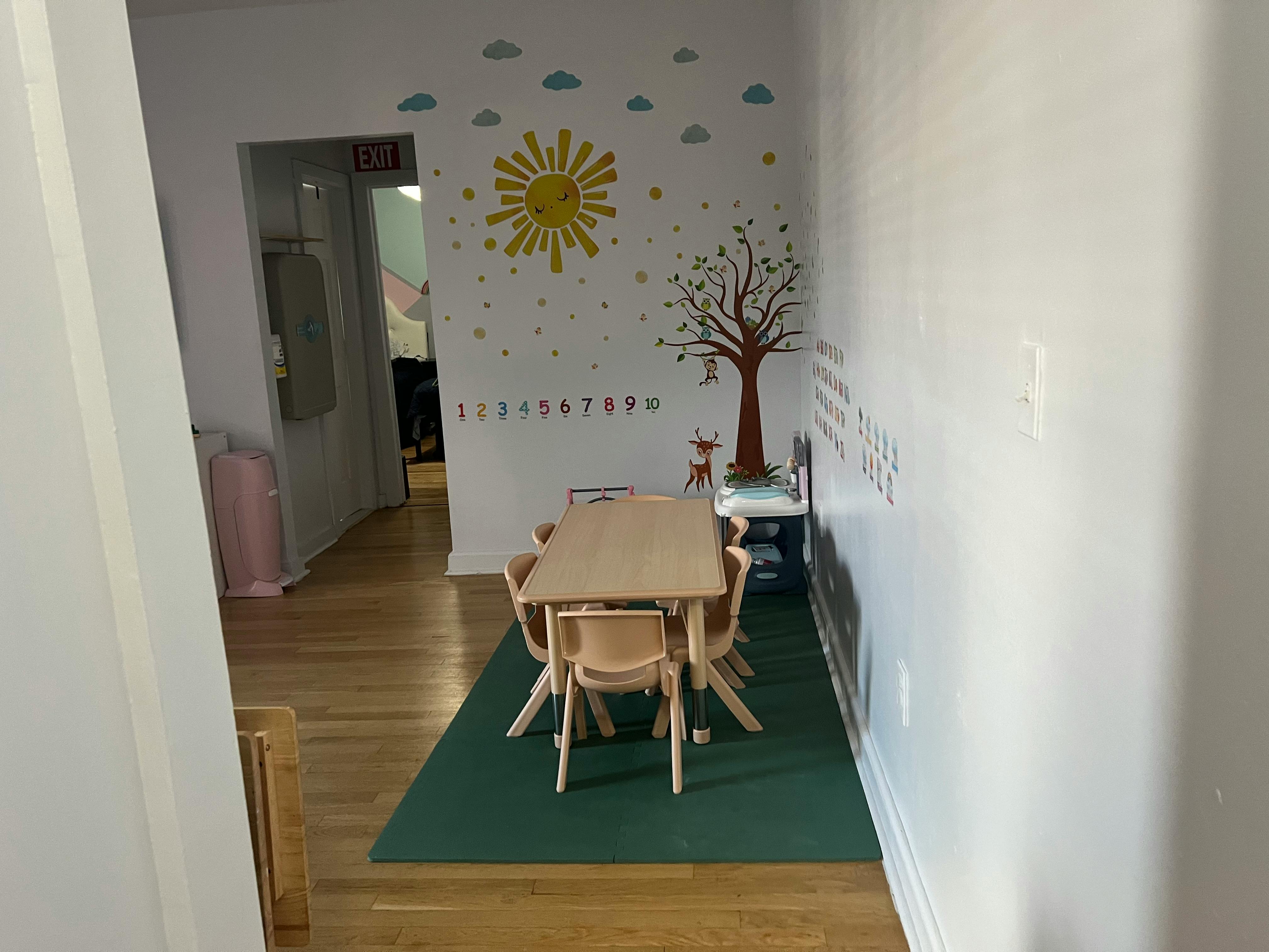 Small table and chairs on a green rug in a room with wall decals