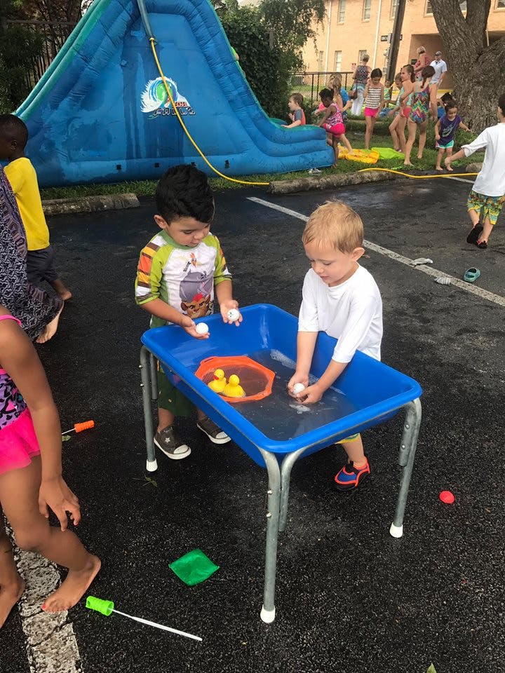 Two children playing with a water table outdoors