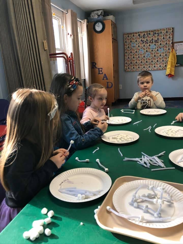 Children at a table making crafts with pipe cleaners and cotton balls