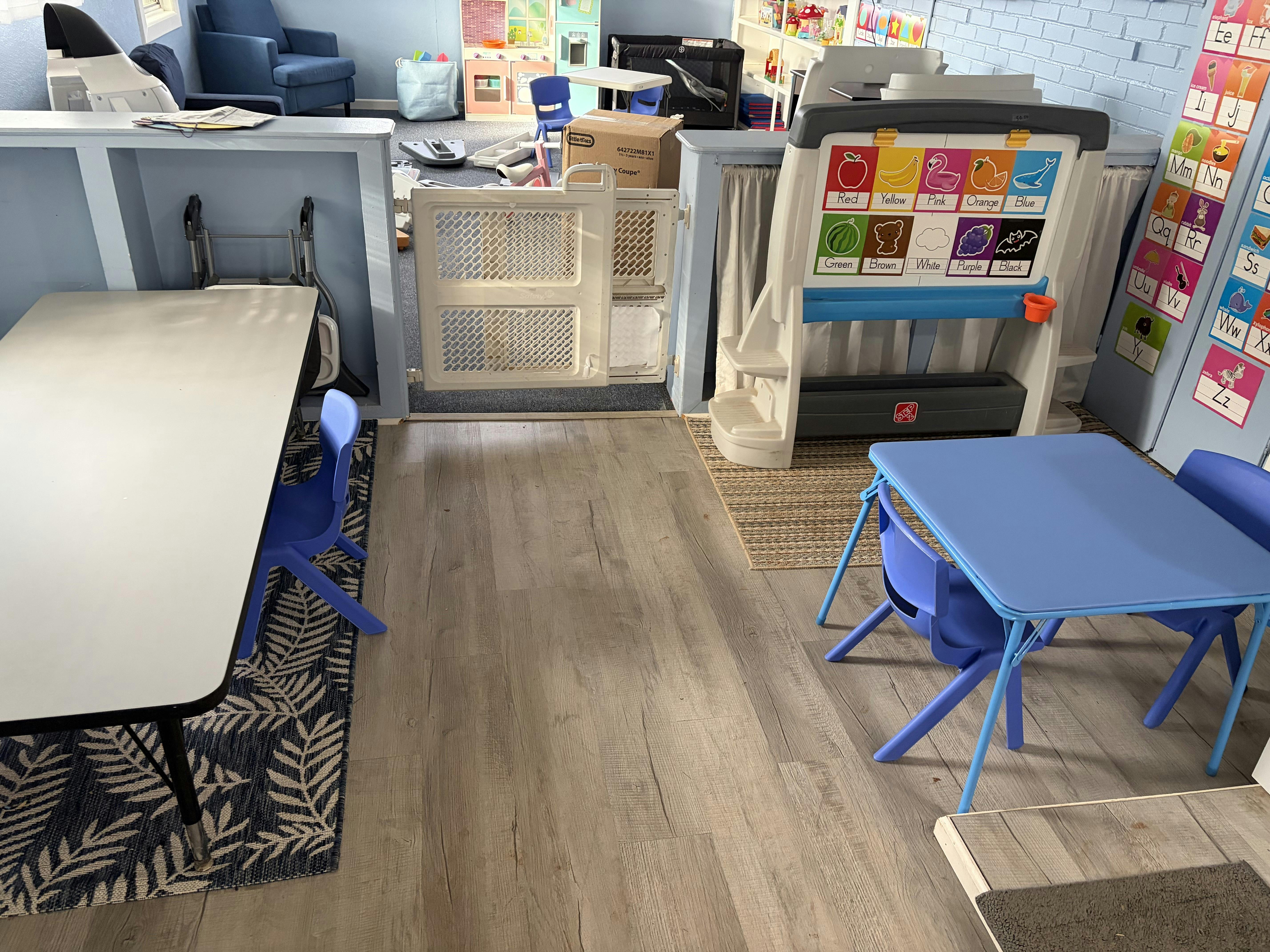 Childcare room with small tables, chairs, and an educational easel