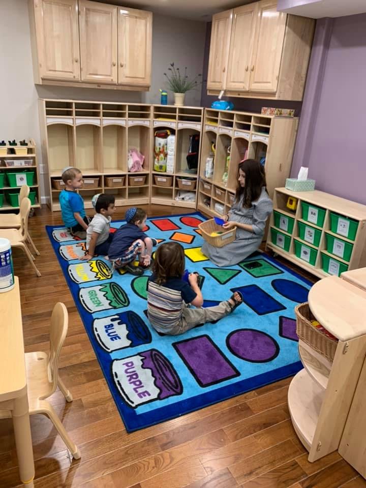 Adult and children sitting on a rug in a classroom