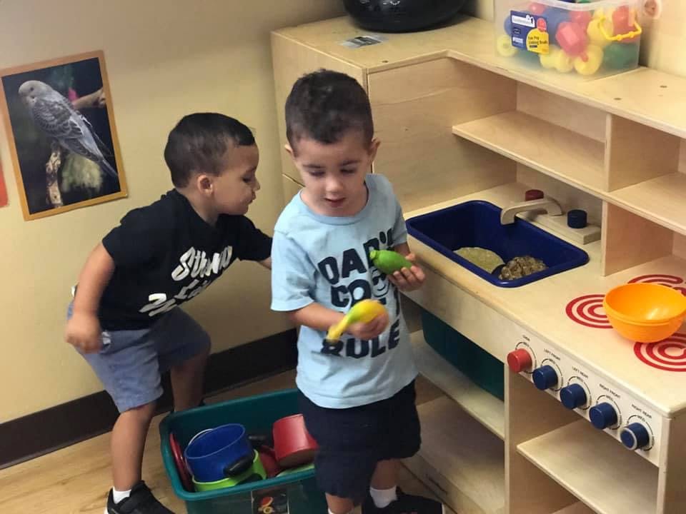 Two children playing with a toy kitchen set