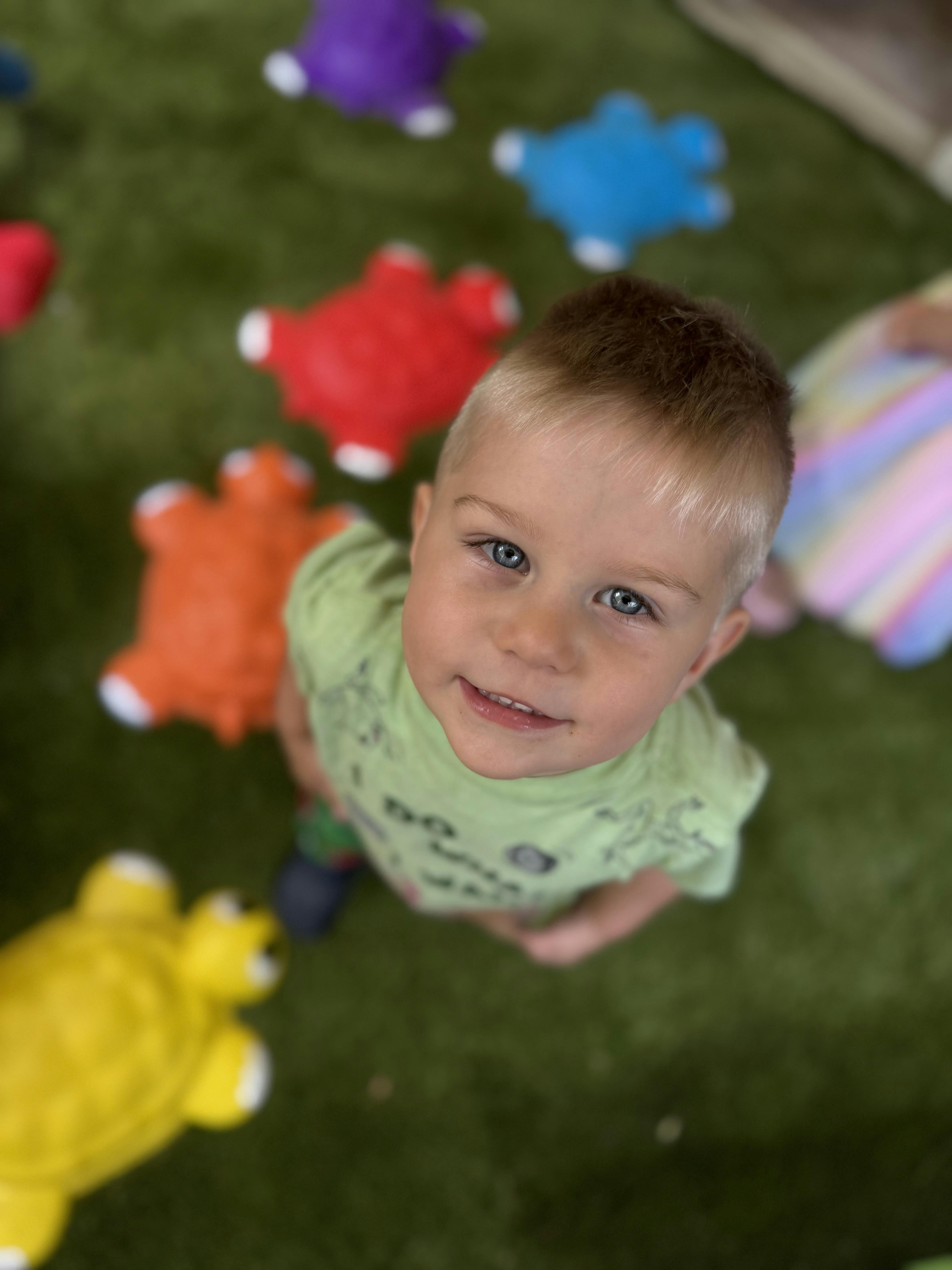 Child looking up at the camera with toys on the floor