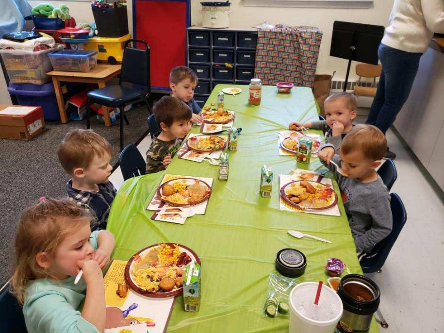 Children eating at a long table in a classroom