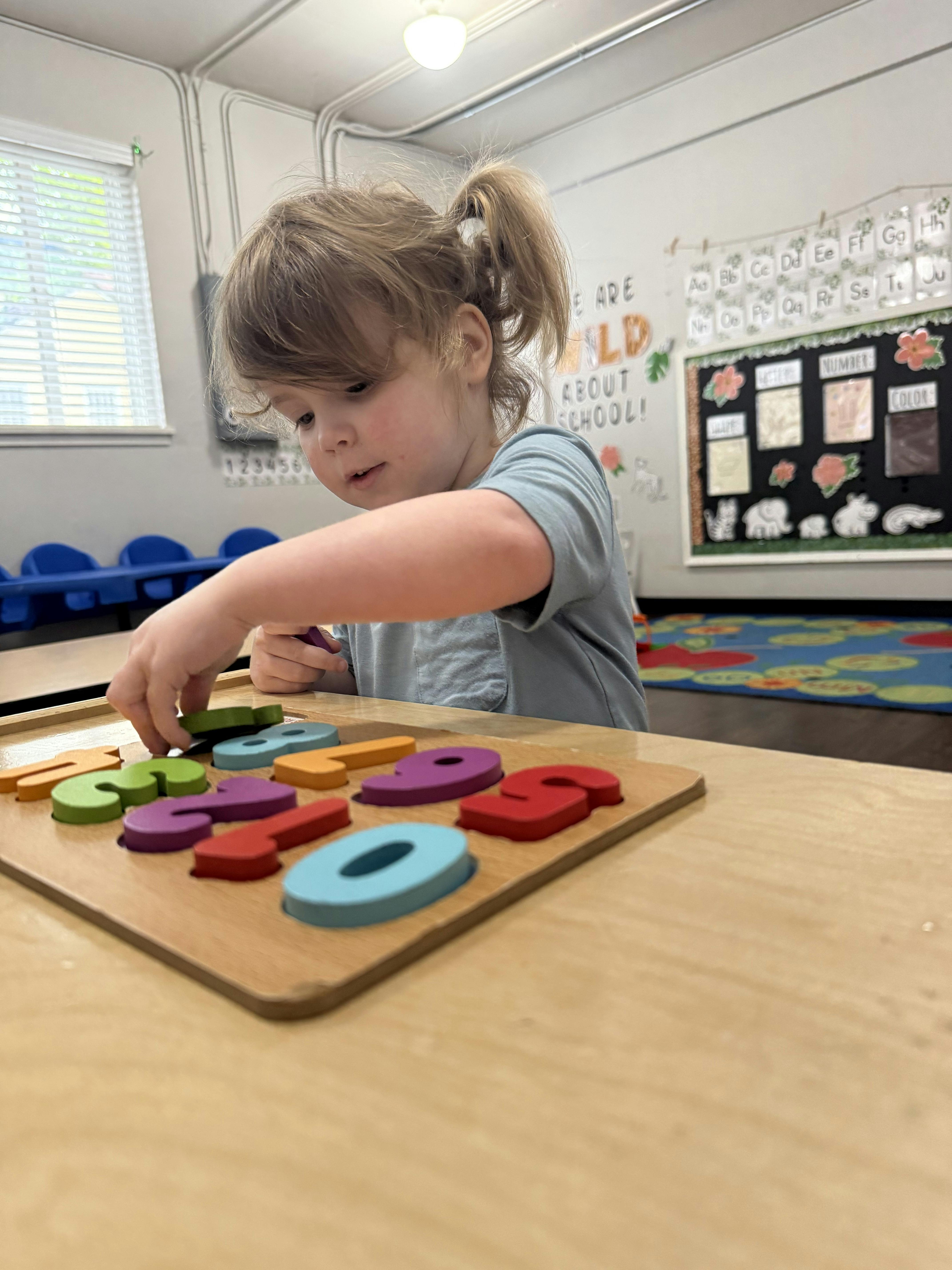 Child playing with a colorful number puzzle on a wooden table