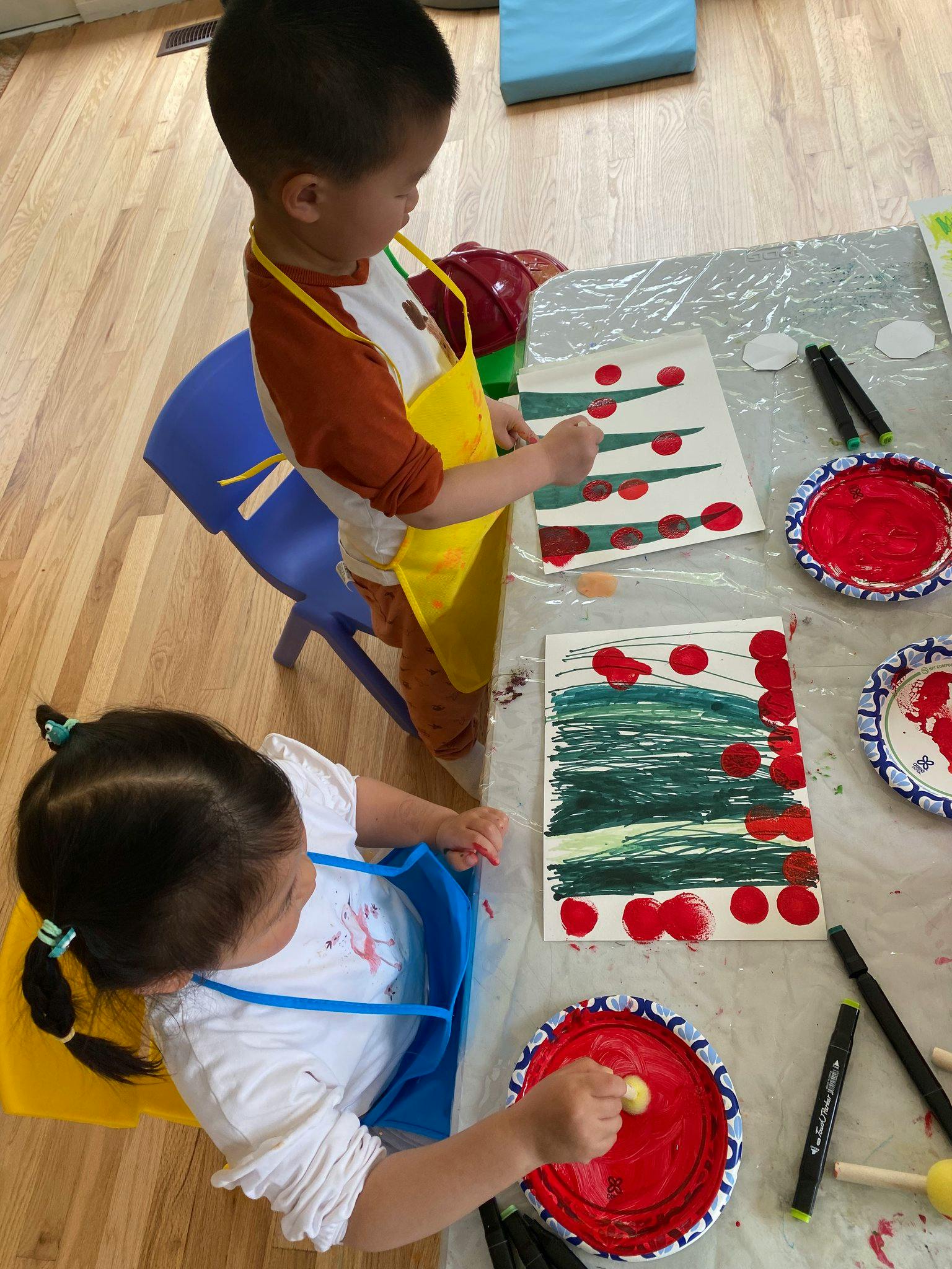 Two children painting at a table in a classroom