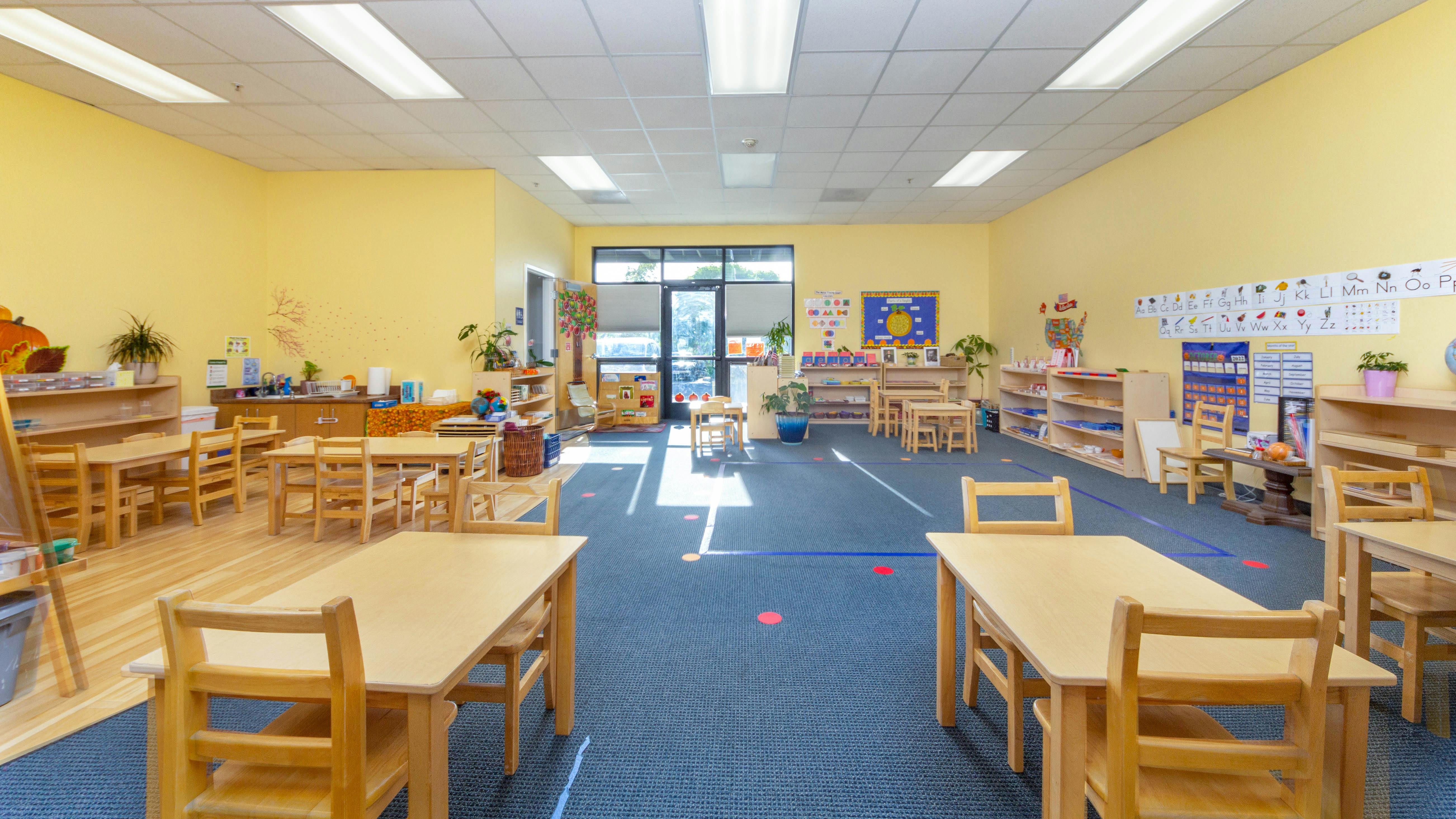 Empty classroom with small wooden tables and chairs