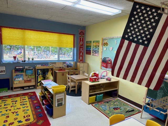 Classroom with an American flag, small tables, chairs, and learning materials