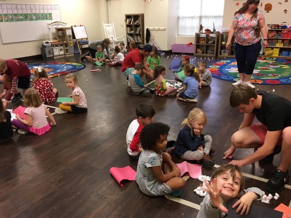 Adults and children sitting on the floor in a classroom