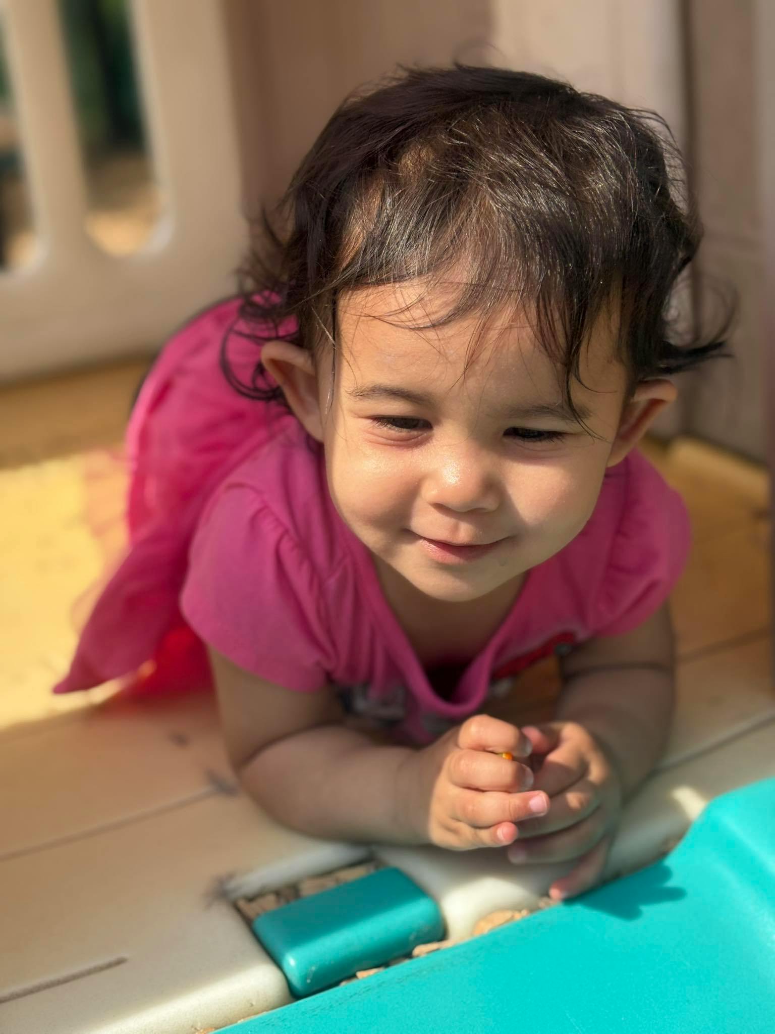 Child in a pink shirt crawling on a light-colored surface