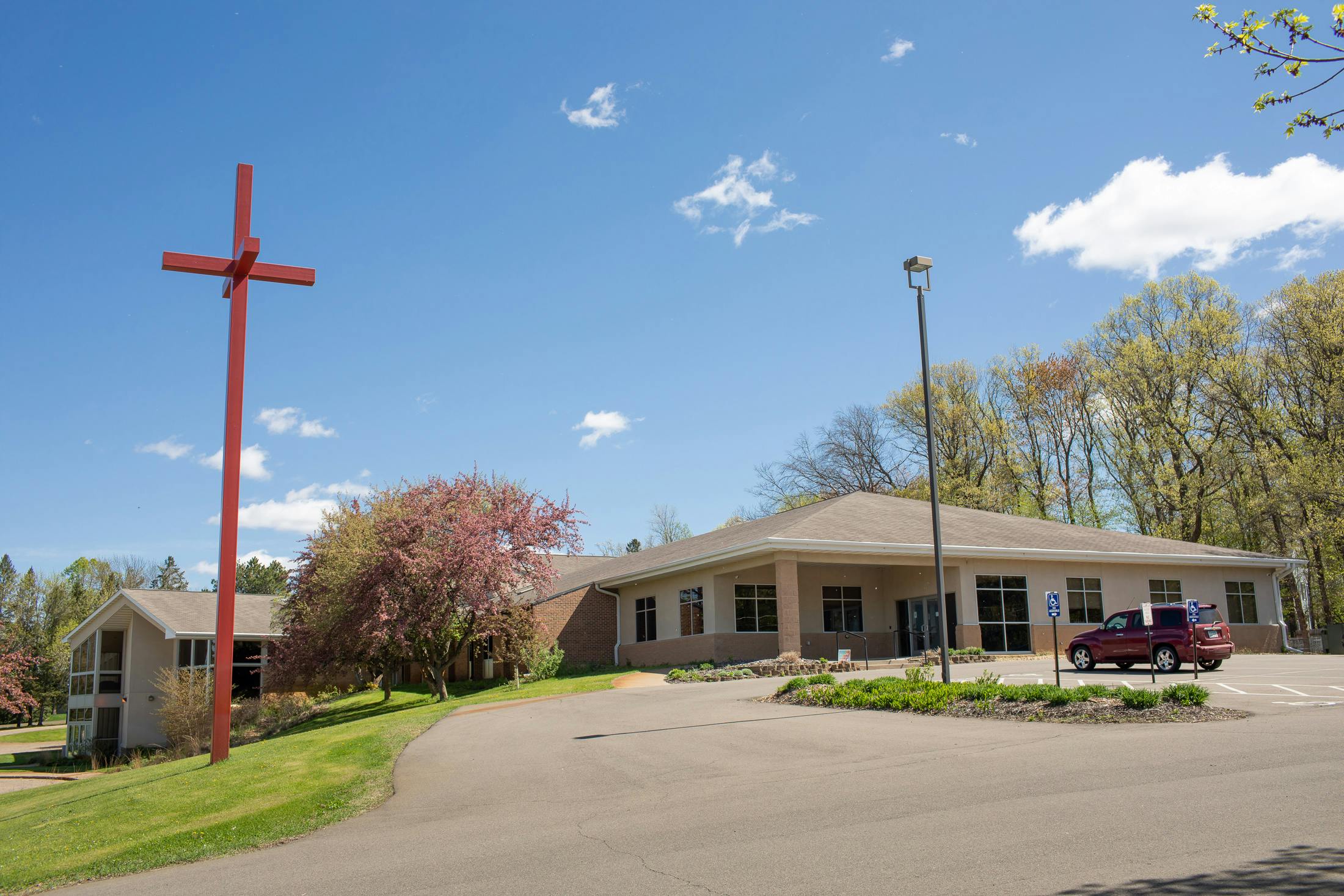 Red cross in front of a building with a parking lot