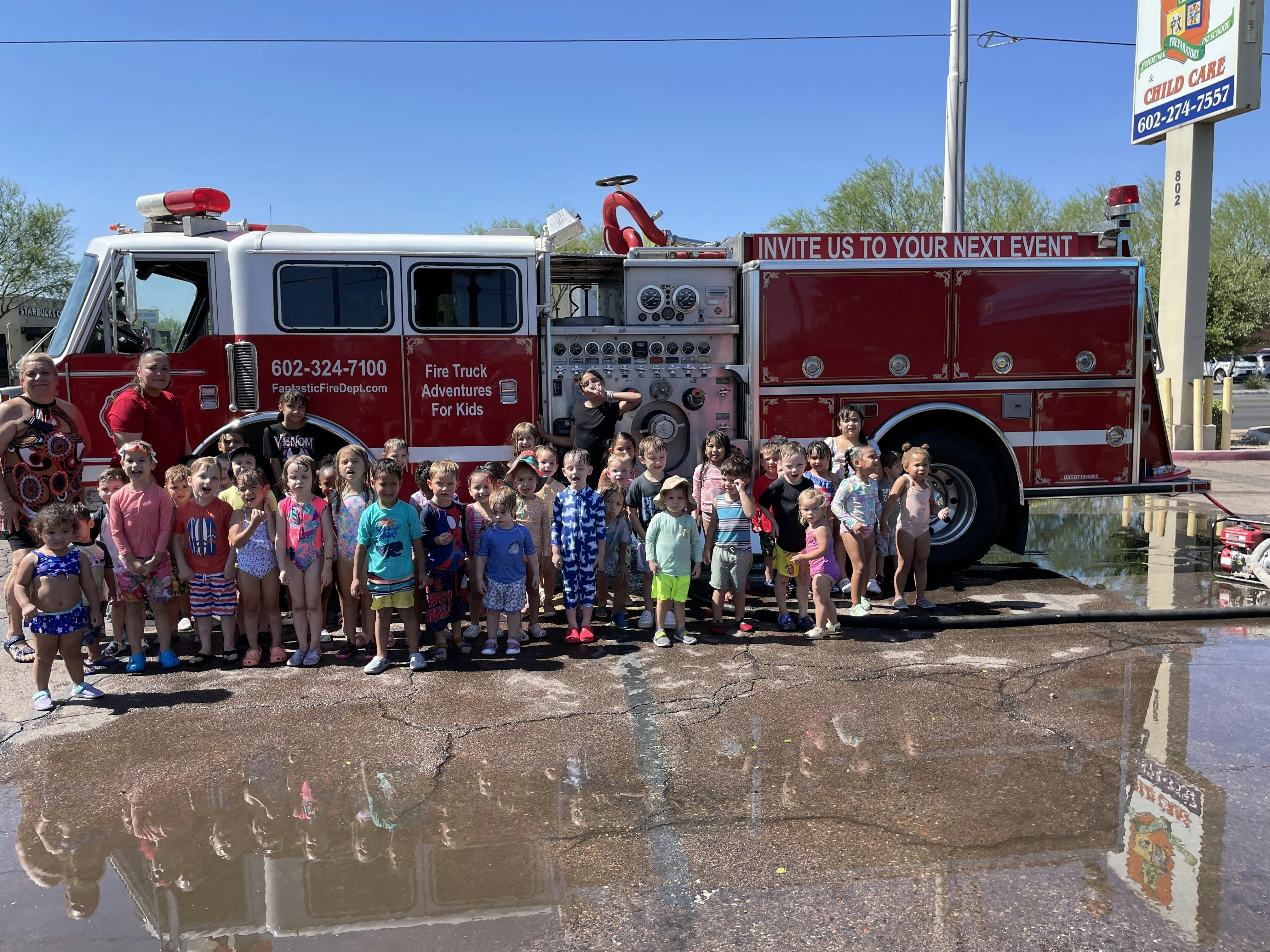 Group of children standing in front of a fire truck in a parking lot