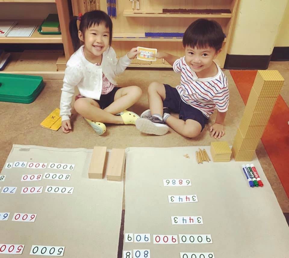 Two children sitting on the floor with math materials