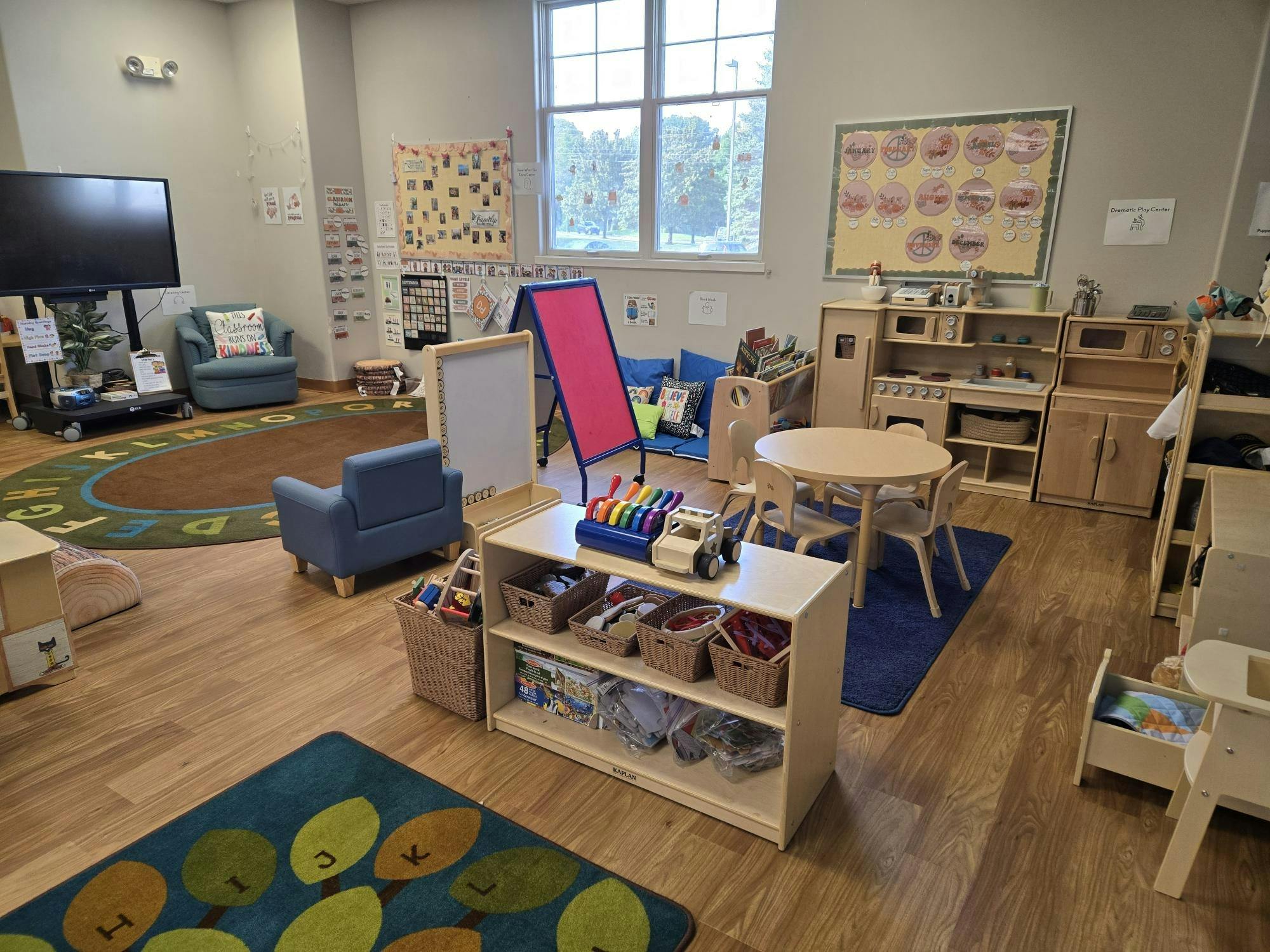 Classroom with small tables, chairs, and shelves with toys and learning materials