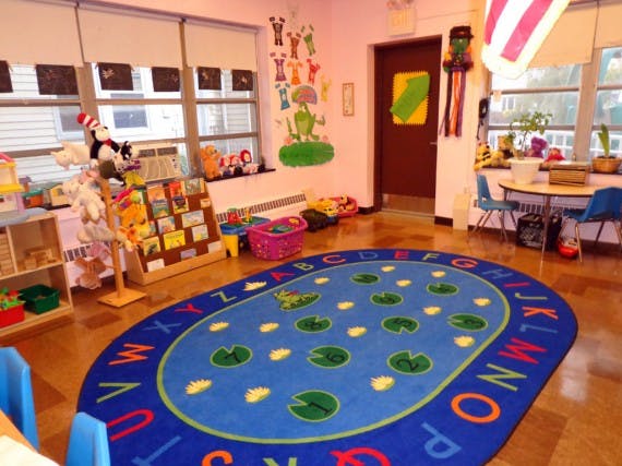 Classroom with a large blue oval rug with letters and lily pads