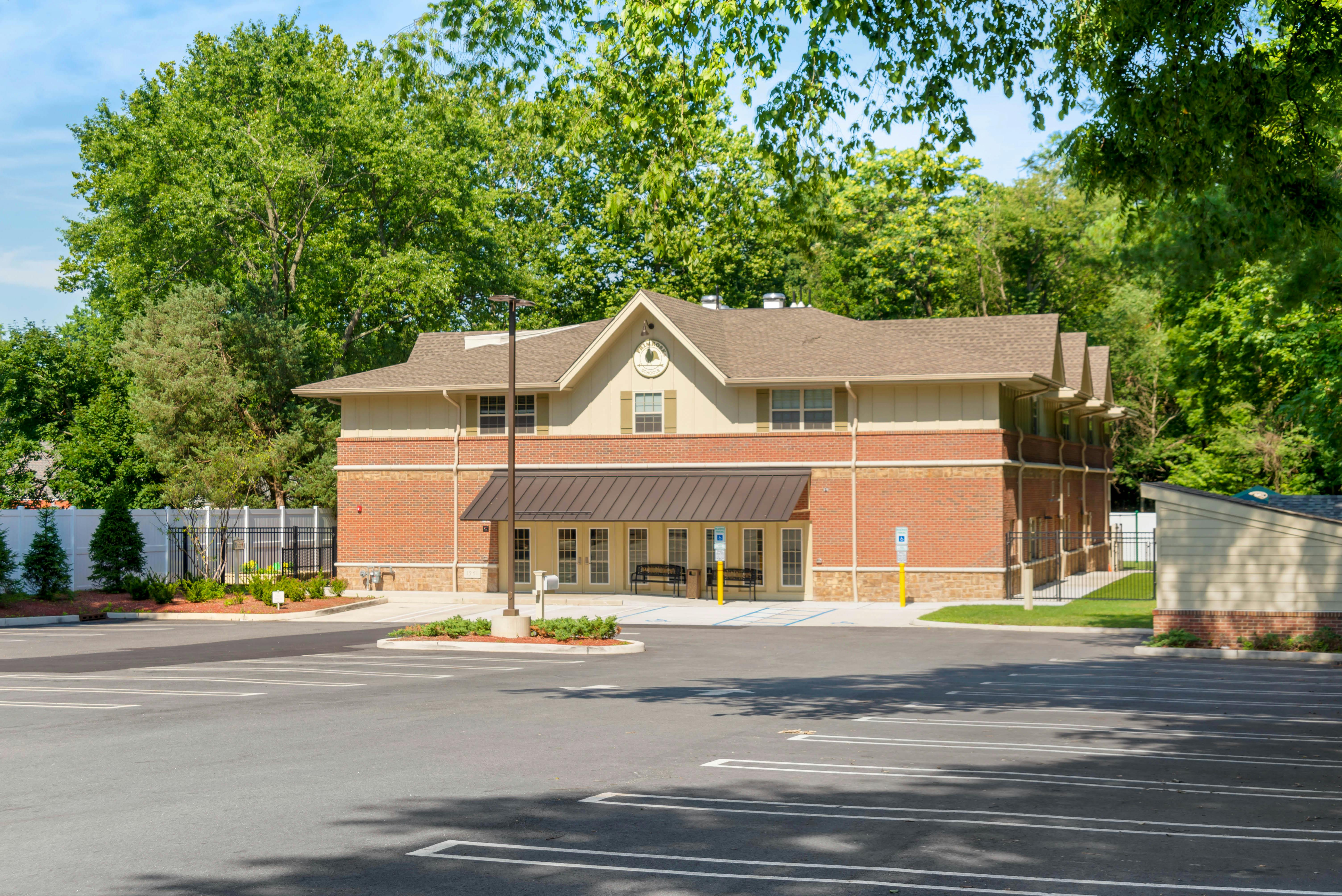 Brick and beige building with a dark brown awning over the entrance and a parking lot