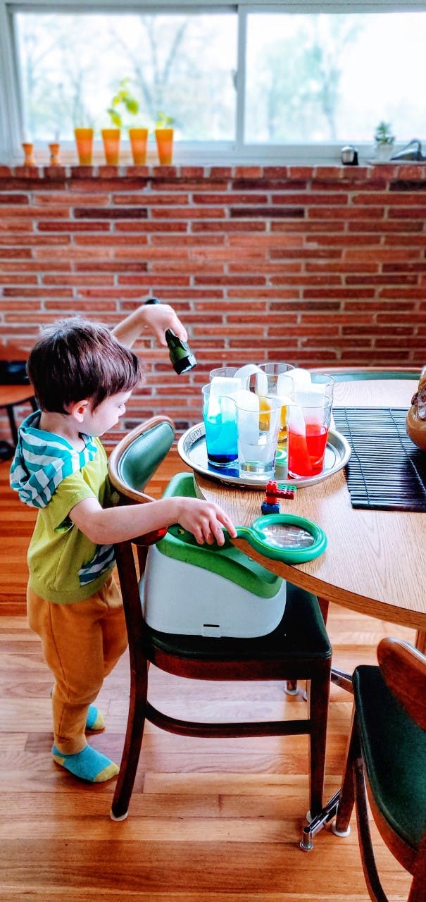 Child pouring liquid from a bottle into a glass on a table
