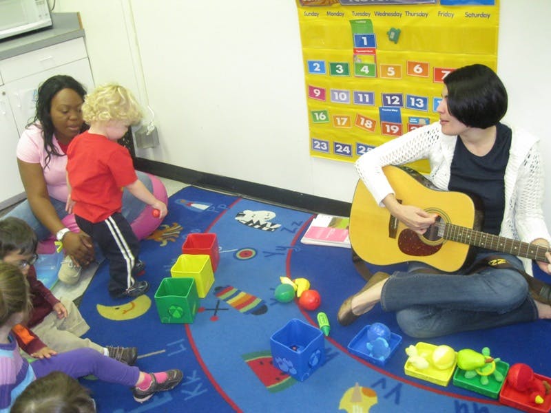 Person playing guitar for children and adult in a classroom