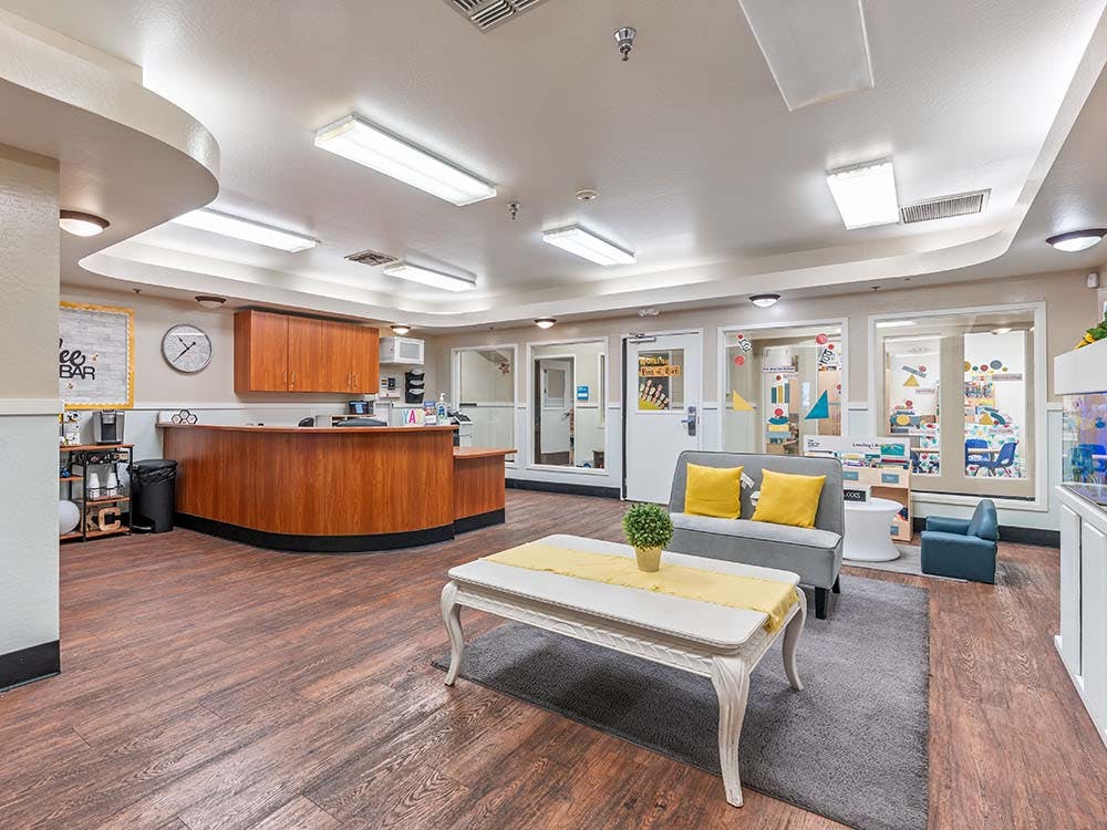 Reception area with a wooden desk and a lounge with yellow pillows