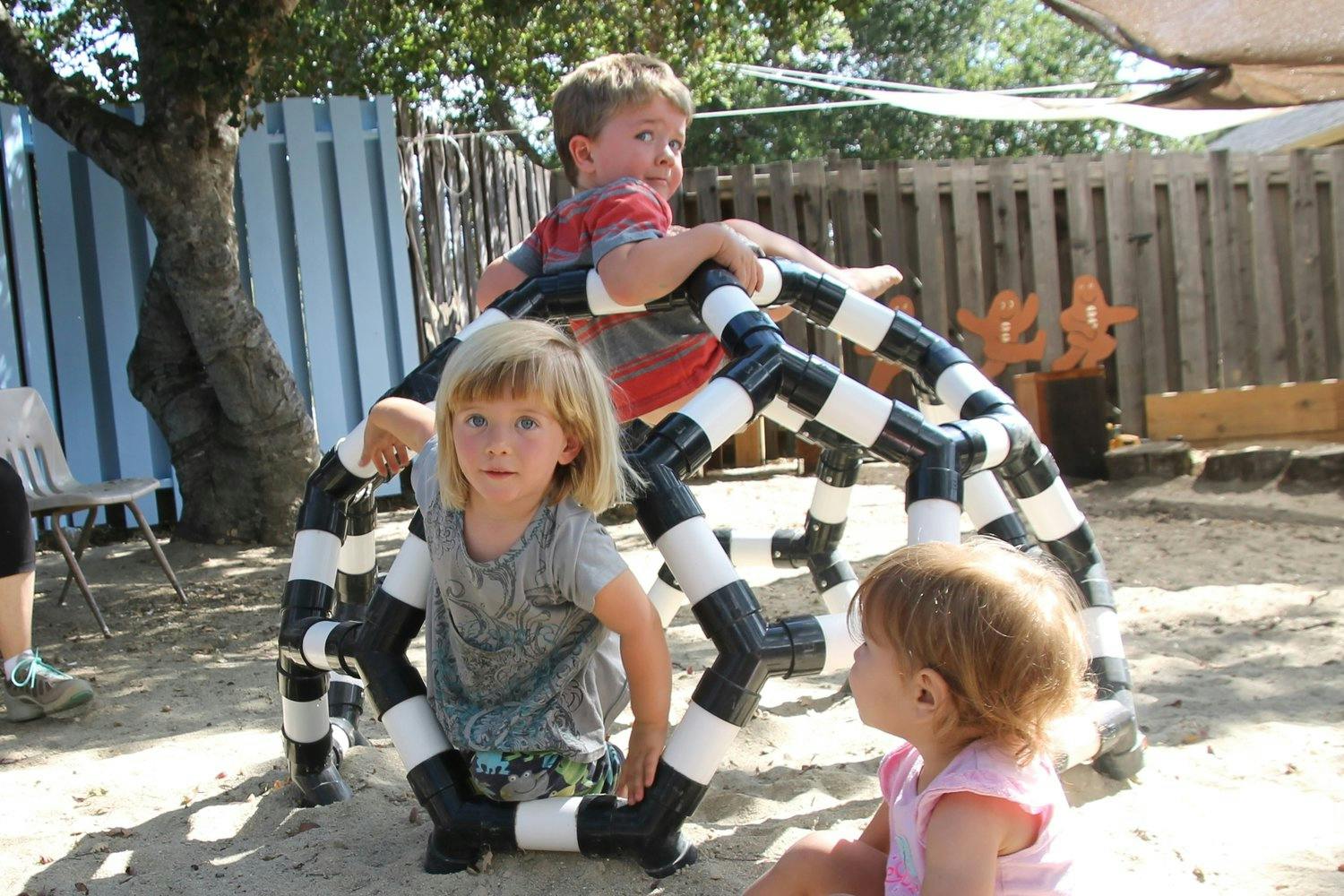 Two children on a black and white striped climbing structure, one child sitting