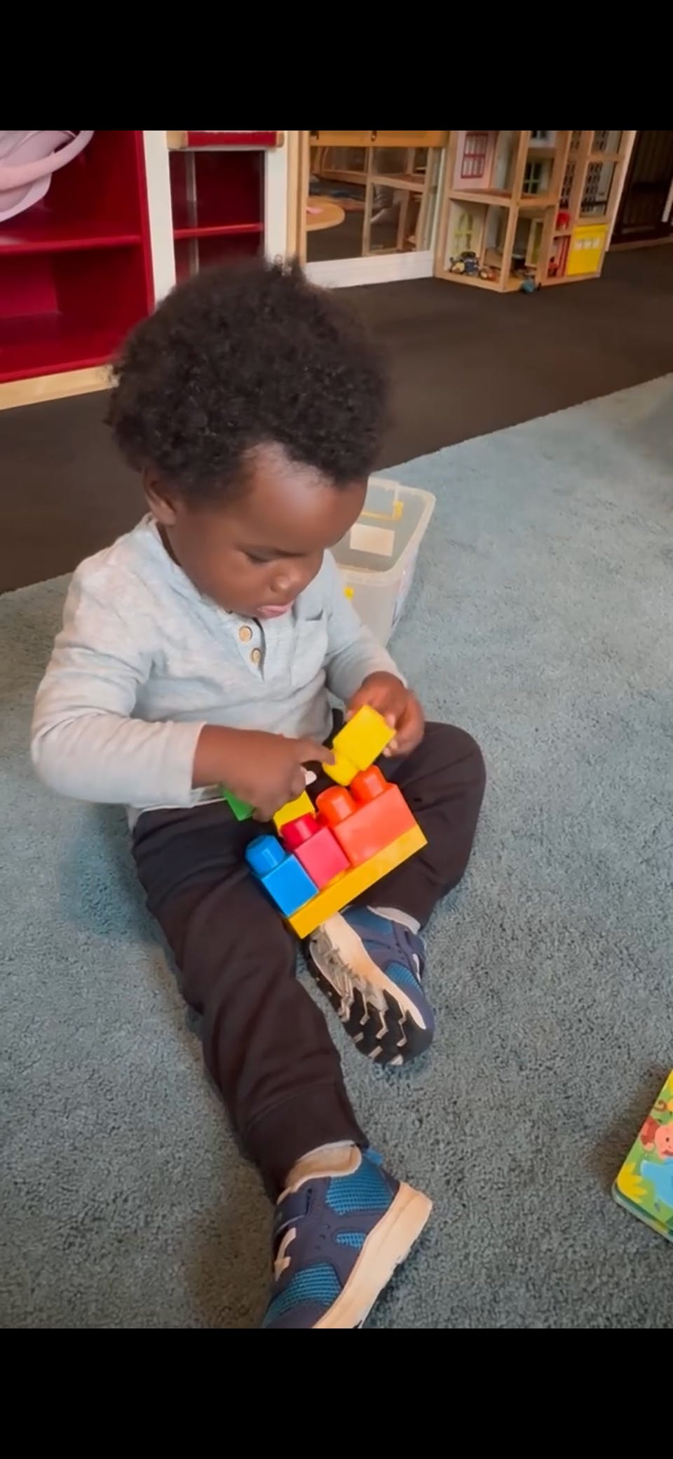 Child playing with colorful plastic building blocks on a rug