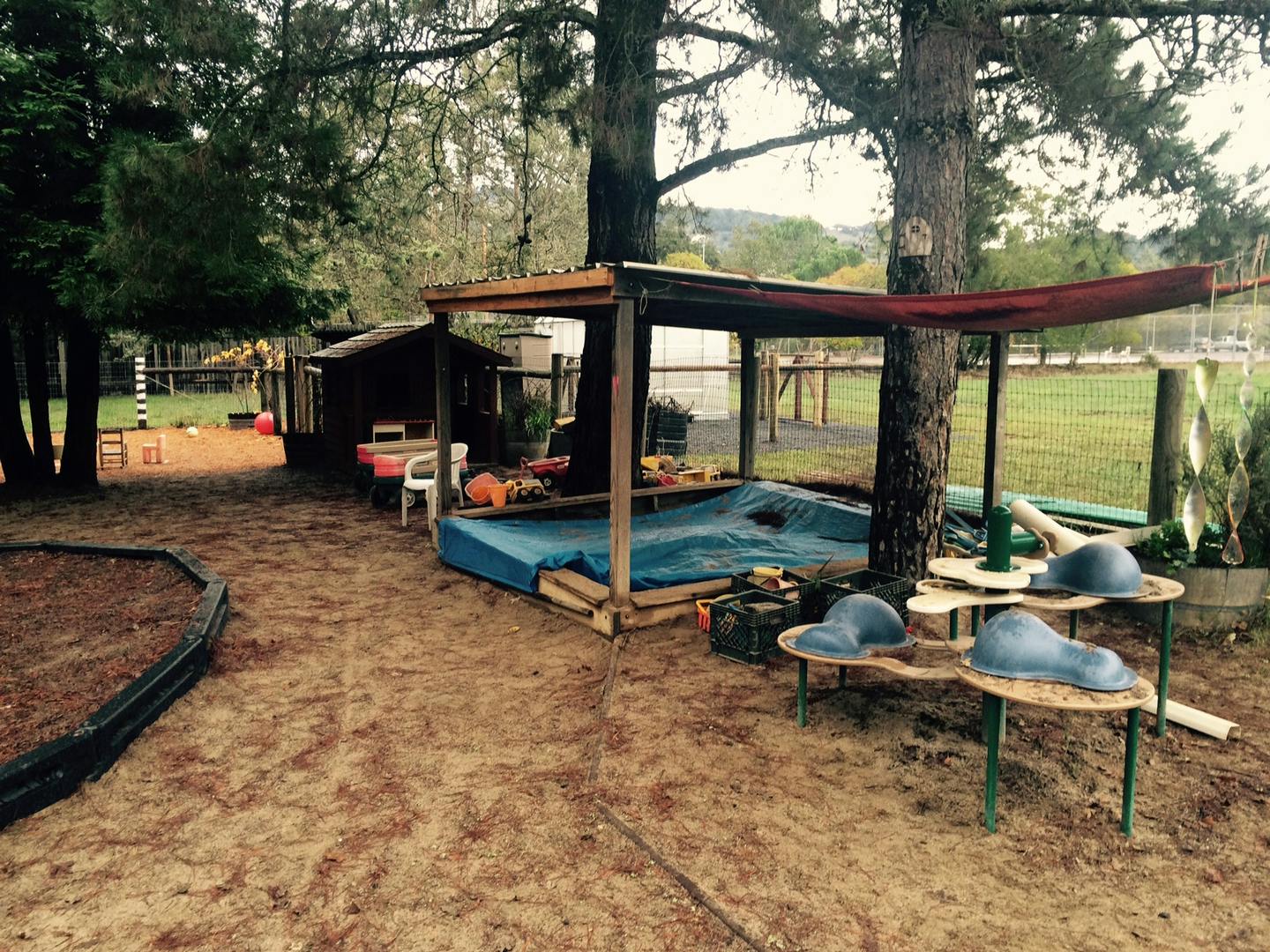 Outdoor play area with a covered sandbox and small tables