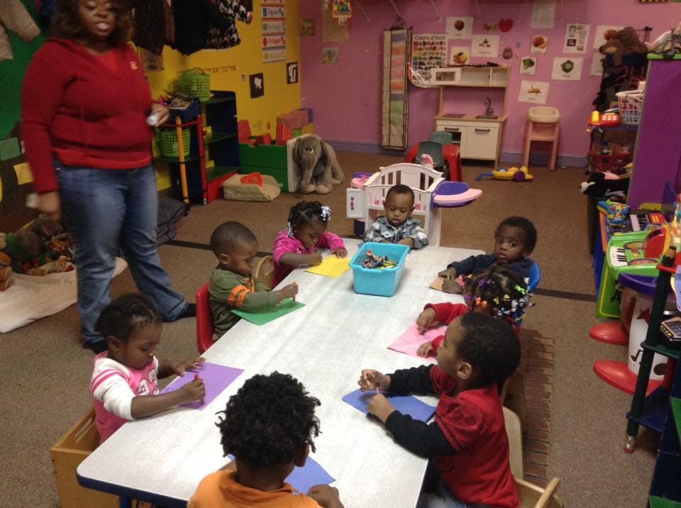 Adult supervising children at a table in a classroom