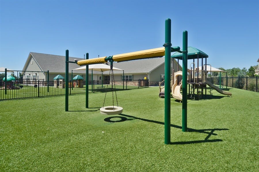 Playground with a tire swing and play structure on artificial turf