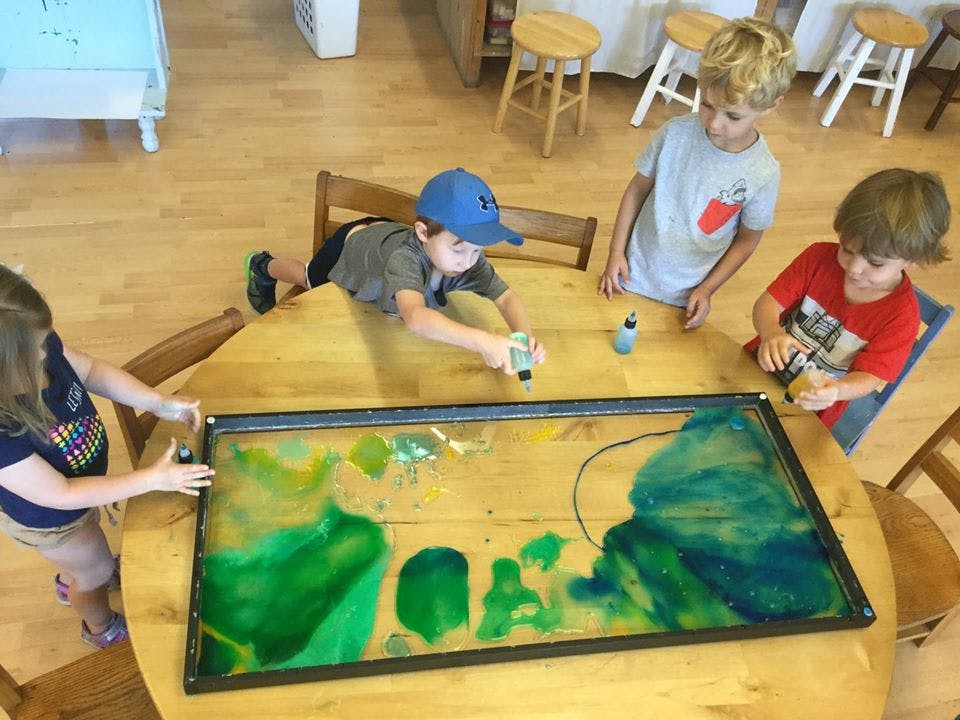 Four children playing with paint on a table