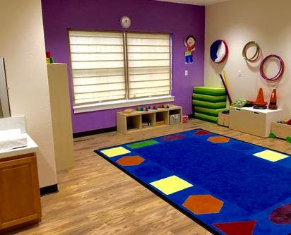 Playroom with a blue rug, window, and various play equipment