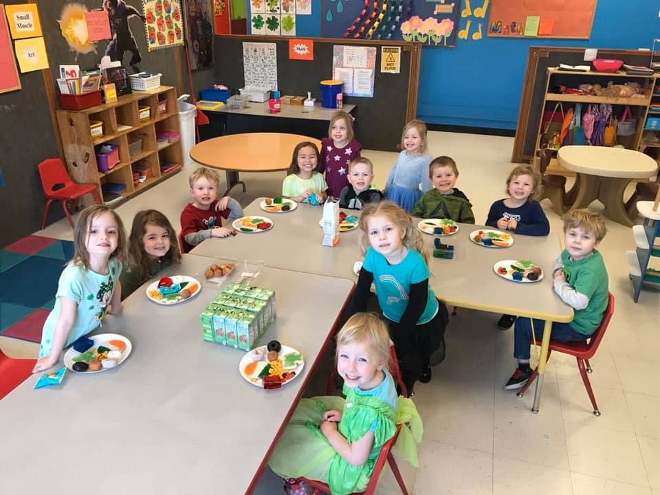 Group of children sitting at tables in a classroom