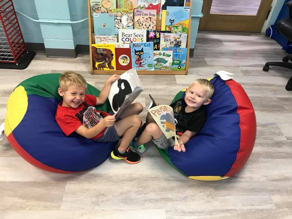 Two children sitting on beanbag chairs reading books