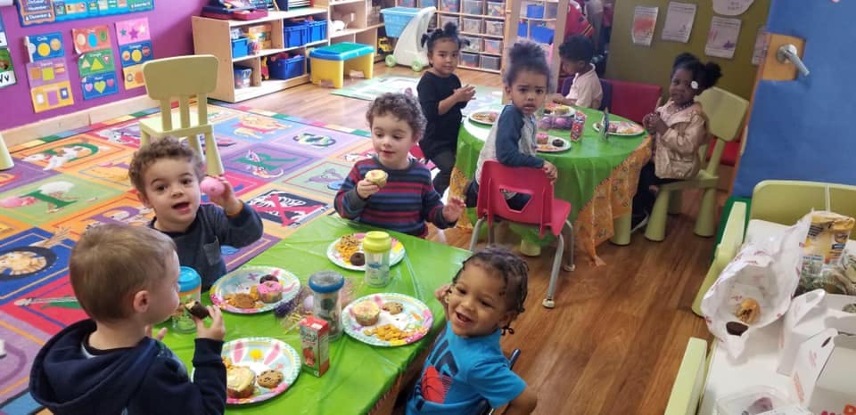 Children eating snacks at tables in a classroom