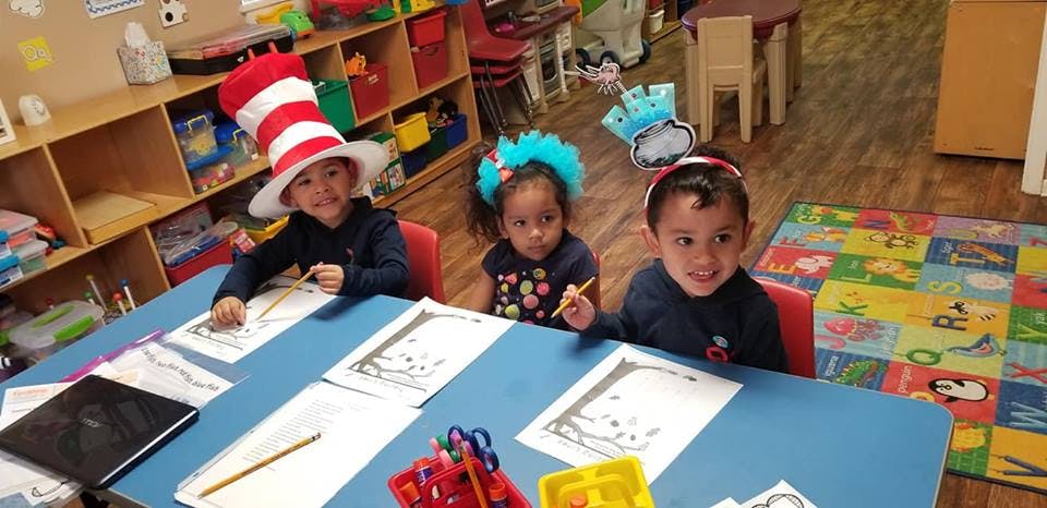 Three children at a table with drawings and art supplies