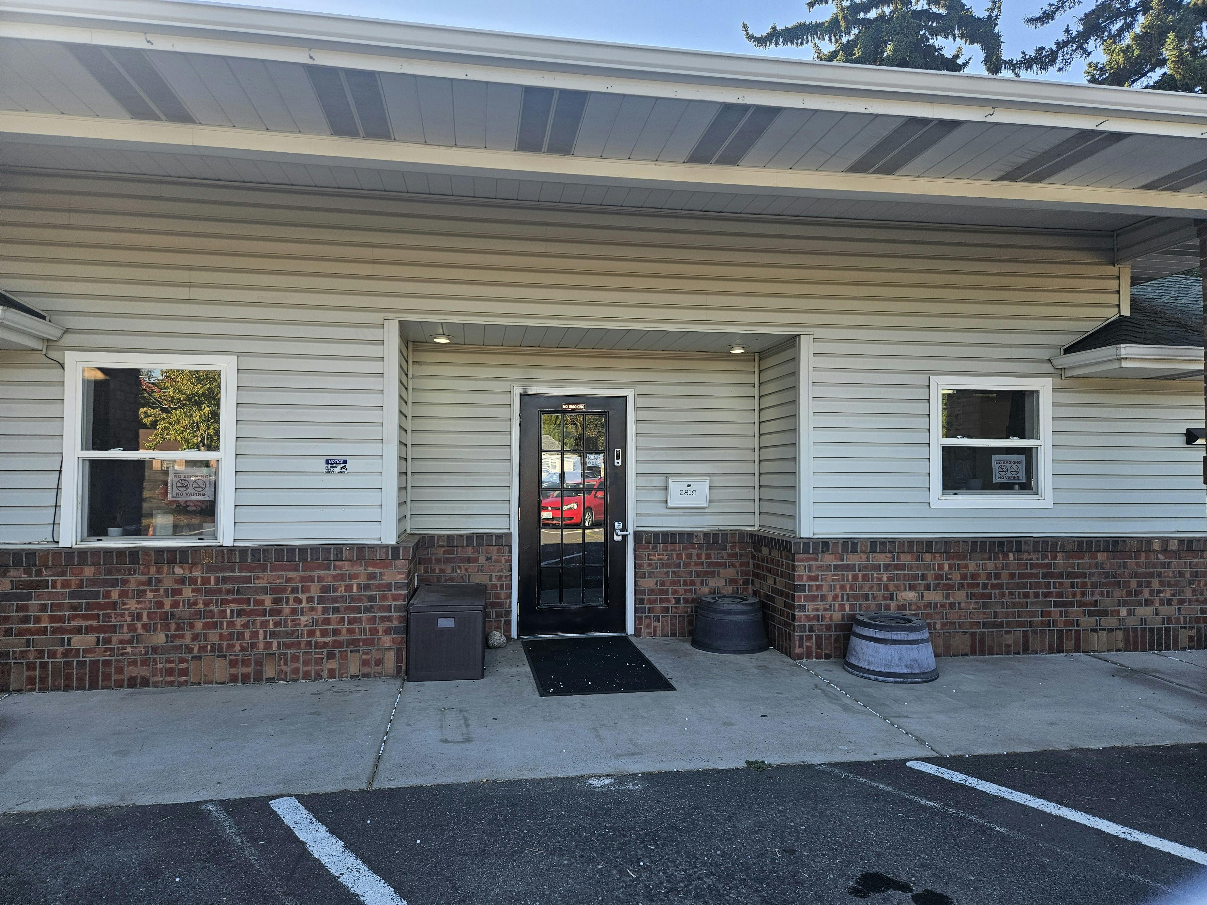 Exterior of a building with light gray siding and a brick base